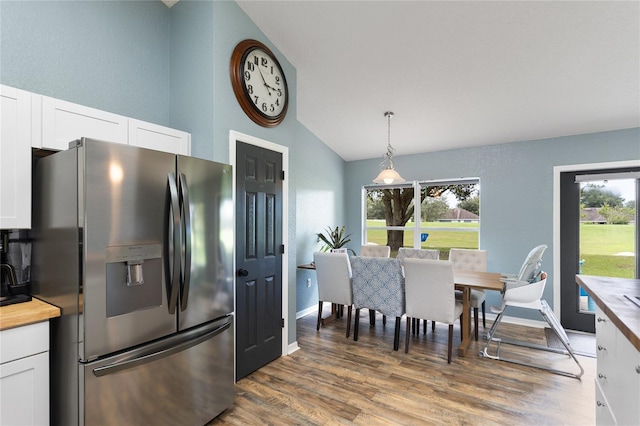 kitchen with white cabinetry, stainless steel fridge, vaulted ceiling, and decorative light fixtures