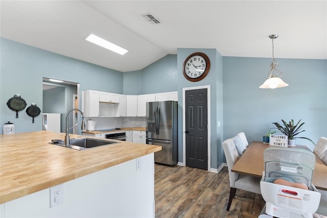 kitchen featuring wooden counters, stainless steel refrigerator with ice dispenser, sink, pendant lighting, and lofted ceiling