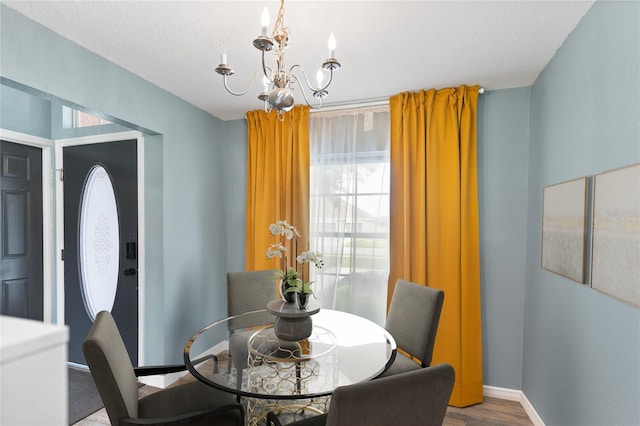 dining space with wood-type flooring, a textured ceiling, and a notable chandelier