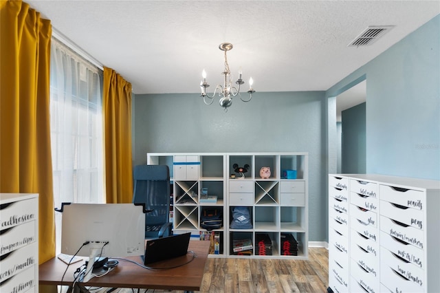 office featuring a notable chandelier, light hardwood / wood-style floors, and a textured ceiling