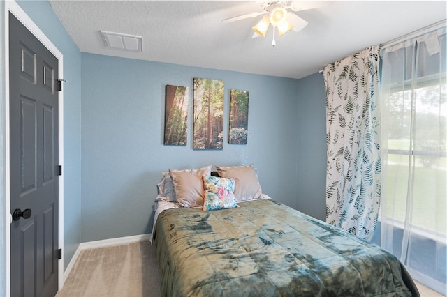 bedroom featuring carpet flooring, multiple windows, ceiling fan, and a textured ceiling