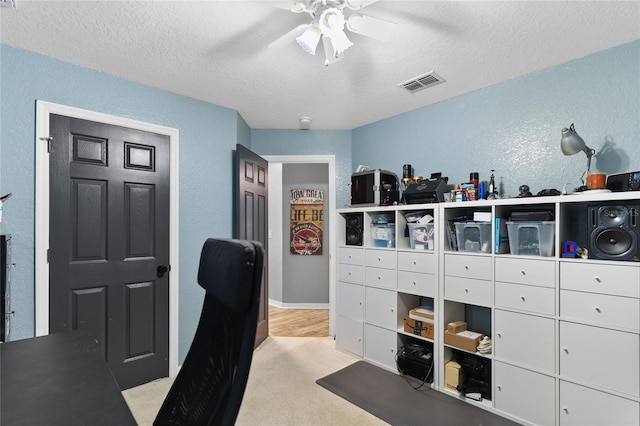 carpeted office with ceiling fan and a textured ceiling