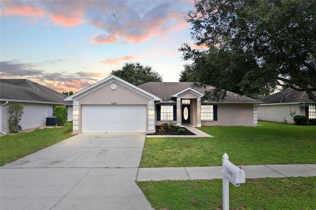 ranch-style home featuring central AC unit, a garage, and a yard