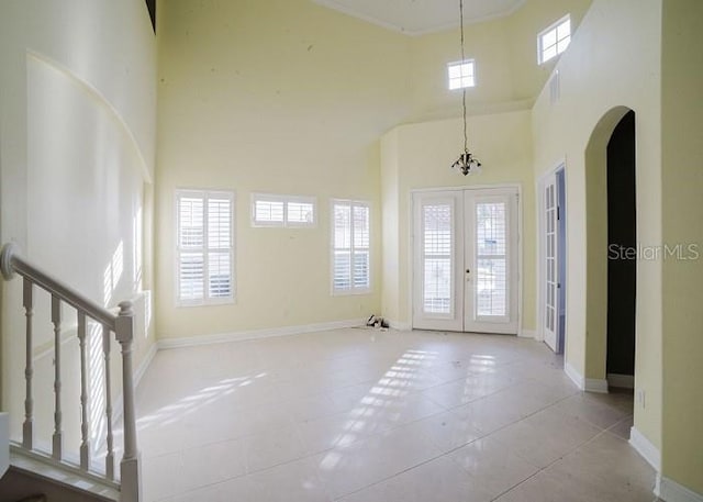 tiled entryway featuring a high ceiling, a wealth of natural light, and french doors