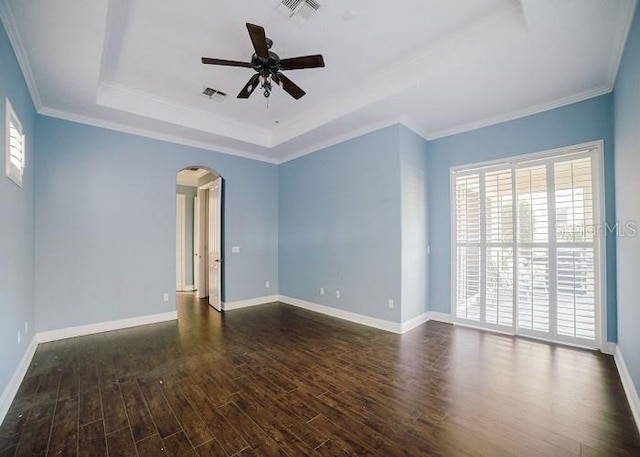 unfurnished room with a tray ceiling, dark wood-type flooring, ornamental molding, and ceiling fan