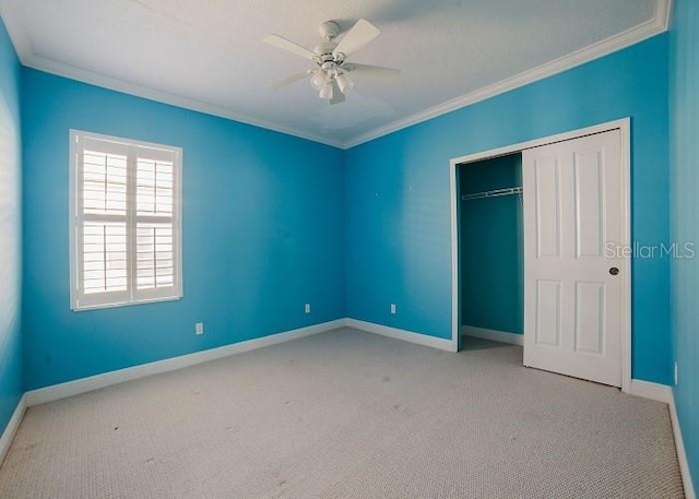 unfurnished bedroom with crown molding, light carpet, ceiling fan, and a closet