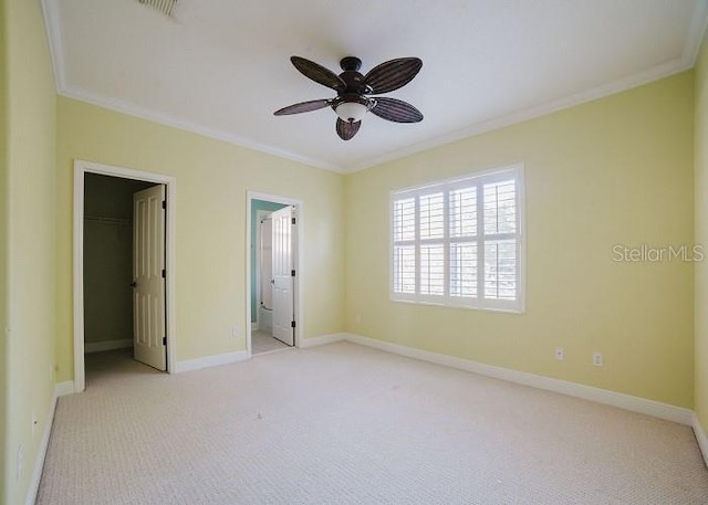 unfurnished bedroom with crown molding, a spacious closet, light colored carpet, and a closet