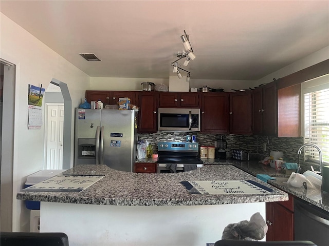 kitchen featuring rail lighting, backsplash, and stainless steel appliances