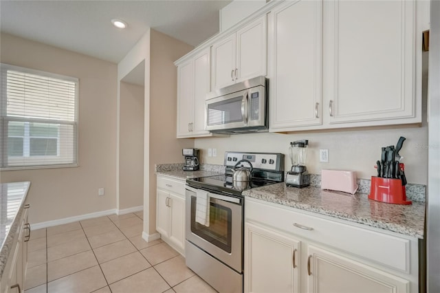 kitchen featuring light stone countertops, stainless steel appliances, white cabinetry, and light tile patterned flooring