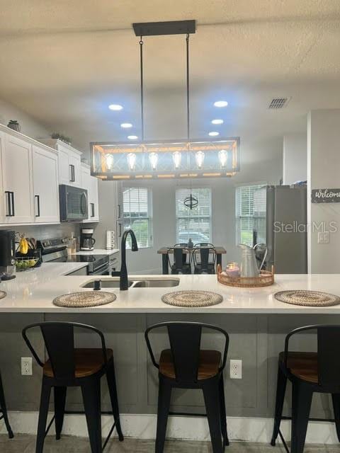 kitchen with stainless steel electric range, a breakfast bar area, kitchen peninsula, and white cabinets