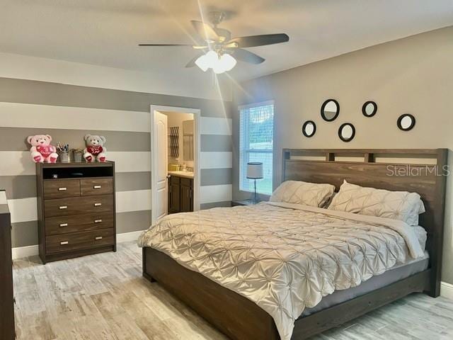 bedroom with light wood-type flooring, ensuite bath, and ceiling fan