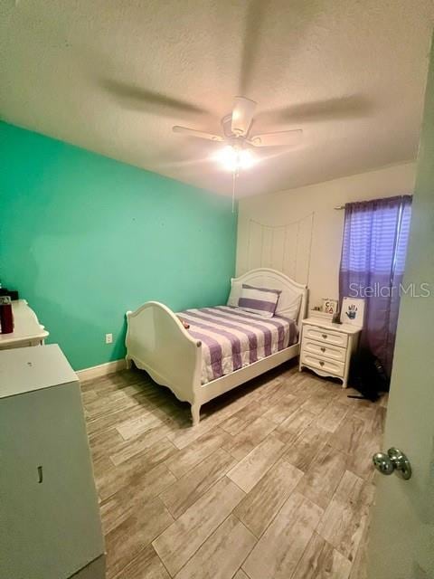 bedroom with a textured ceiling, light hardwood / wood-style flooring, and ceiling fan