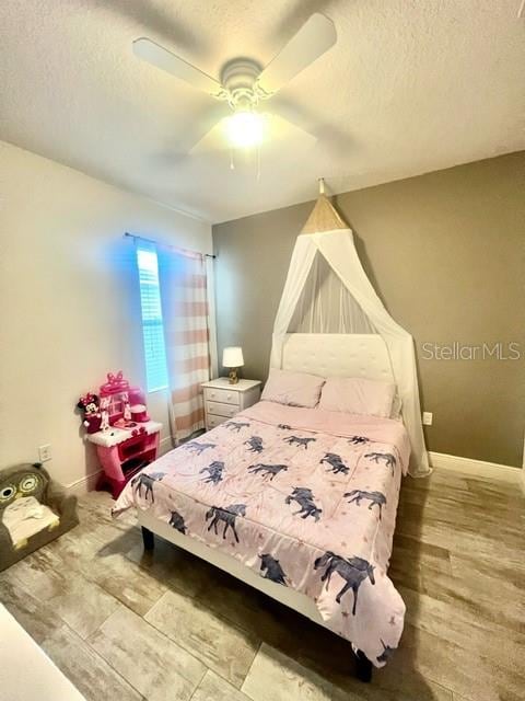 bedroom featuring ceiling fan, wood-type flooring, and a textured ceiling