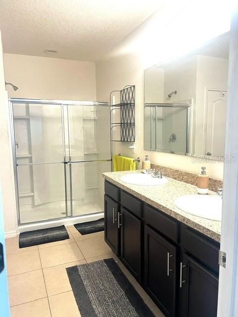 bathroom with tile patterned flooring, walk in shower, a textured ceiling, and vanity