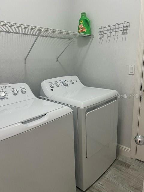 laundry room featuring washing machine and clothes dryer and hardwood / wood-style floors