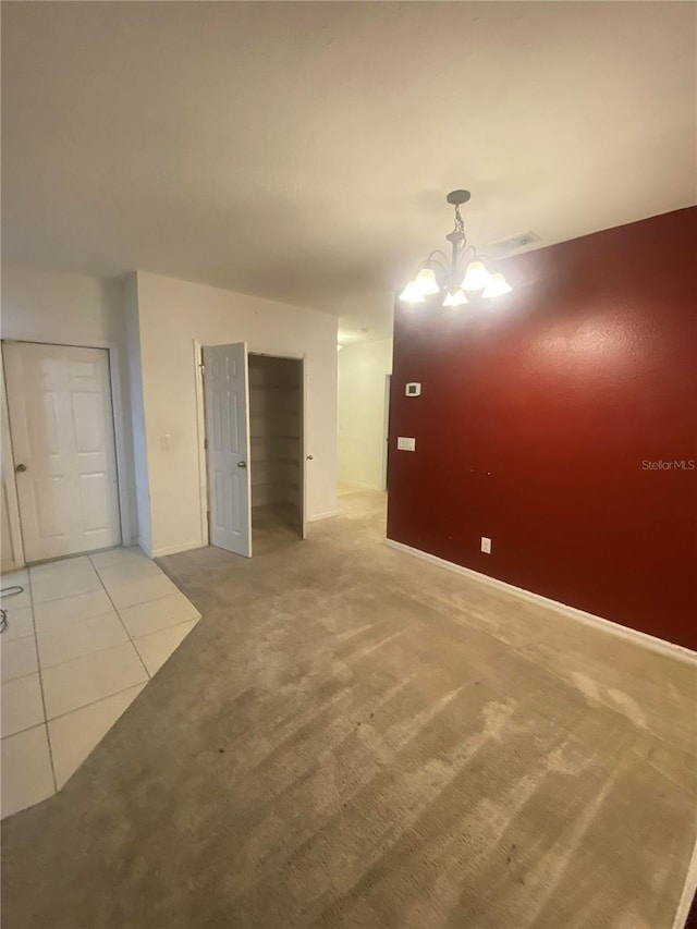 spare room with a chandelier and carpet flooring