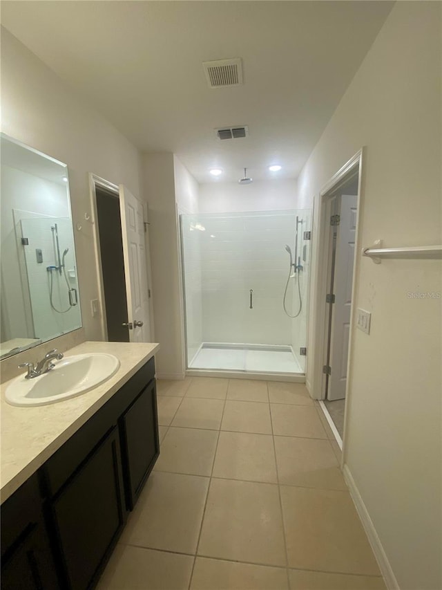 bathroom with vanity, a tile shower, and tile patterned flooring