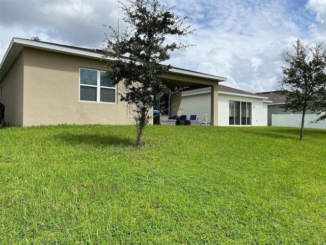 back of house with a lawn and a patio