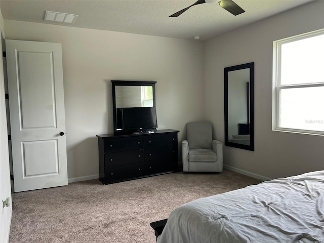 bedroom featuring ceiling fan, multiple windows, a textured ceiling, and carpet