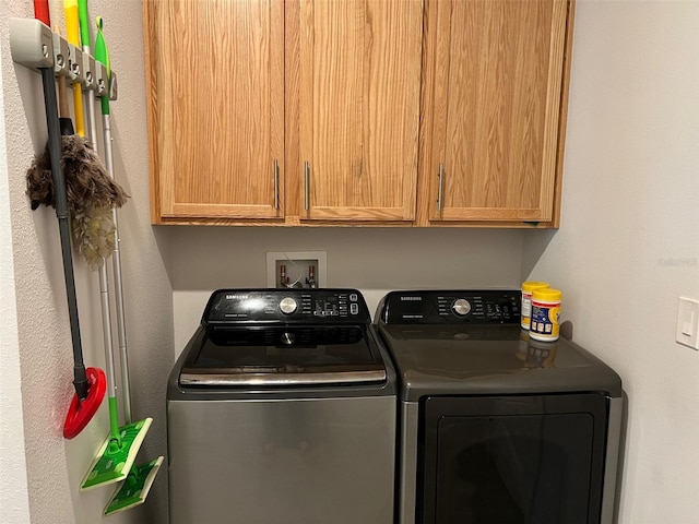 clothes washing area featuring washer and clothes dryer and cabinets