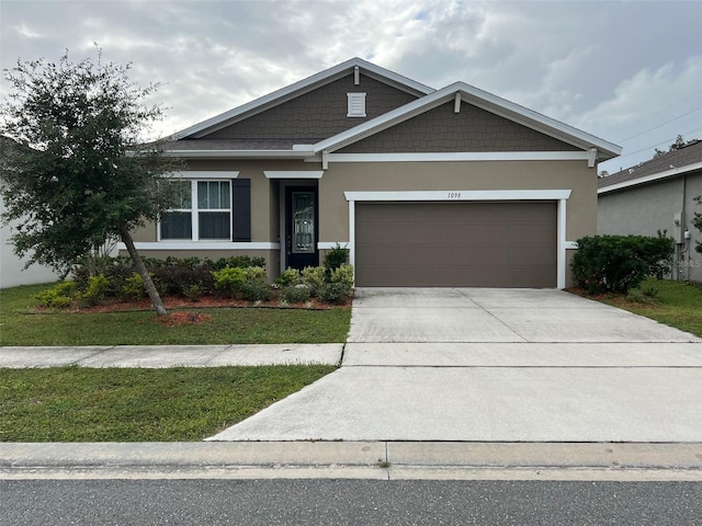 craftsman-style home featuring stucco siding, a garage, concrete driveway, and a front yard