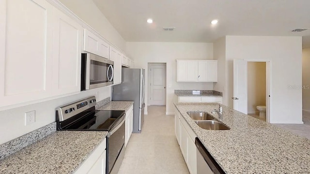 kitchen featuring white cabinetry, light stone countertops, stainless steel appliances, and sink