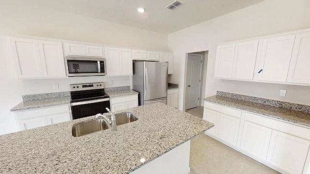 kitchen with white cabinetry, light stone counters, stainless steel appliances, and sink