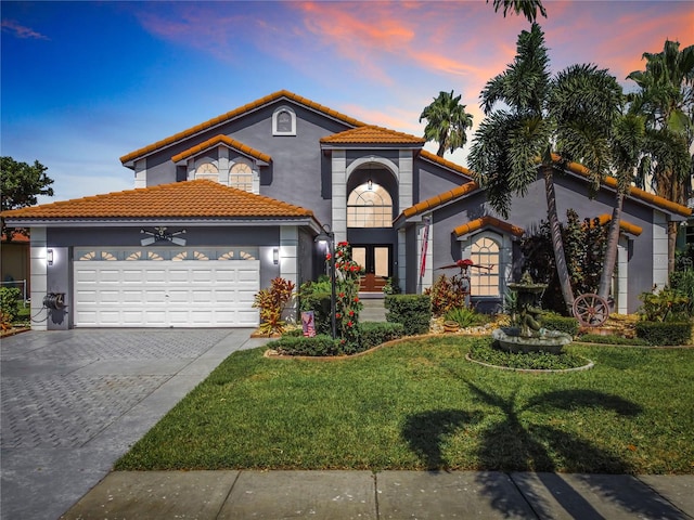 mediterranean / spanish-style home featuring a garage and a lawn