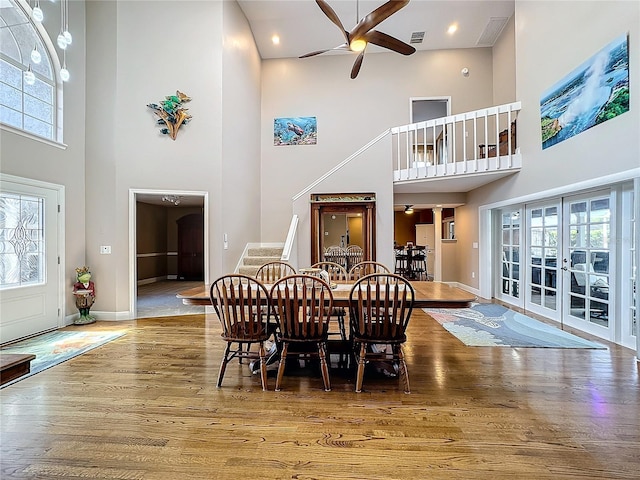 dining area with a healthy amount of sunlight, a high ceiling, and hardwood / wood-style flooring