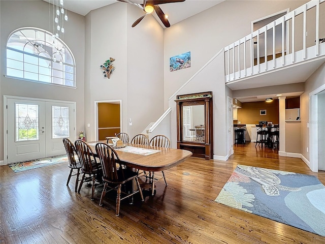 dining room featuring a towering ceiling, wood-type flooring, french doors, and ceiling fan