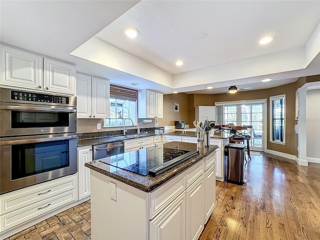 kitchen featuring a wealth of natural light, appliances with stainless steel finishes, white cabinetry, and a center island