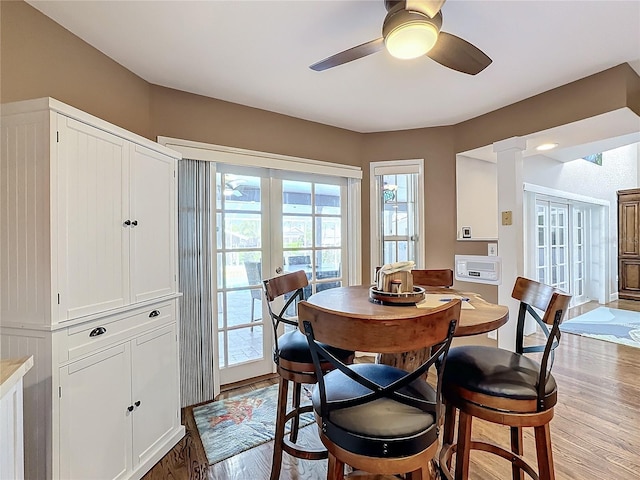 dining space featuring french doors, decorative columns, light hardwood / wood-style floors, and ceiling fan