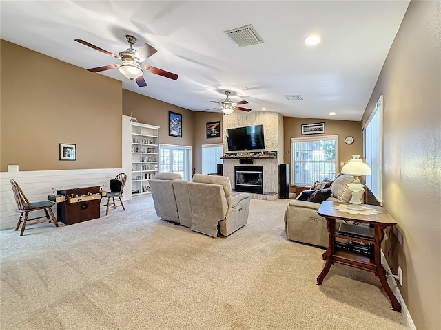 carpeted living room featuring ceiling fan, lofted ceiling, and a large fireplace