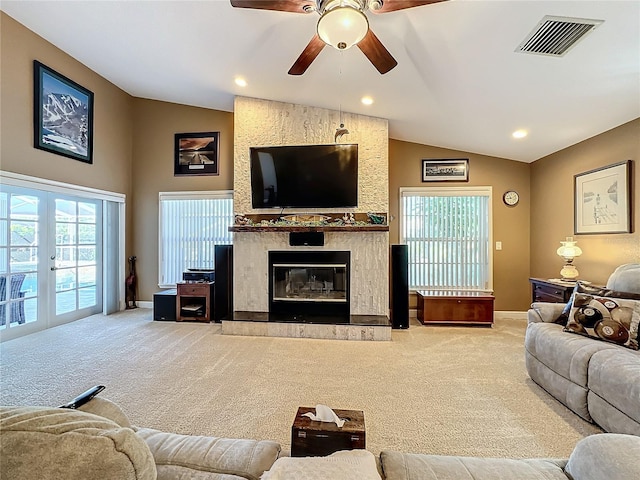 carpeted living room featuring ceiling fan, lofted ceiling, french doors, and a large fireplace