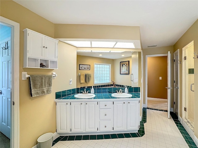 bathroom with walk in shower, vanity, and tile patterned floors