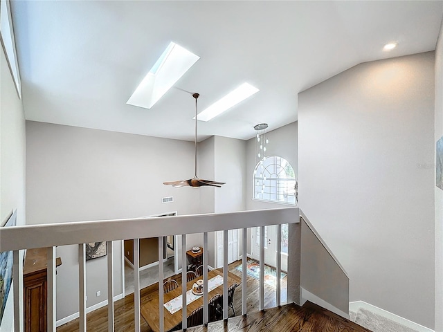 corridor featuring hardwood / wood-style flooring and vaulted ceiling with skylight