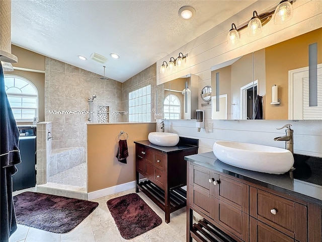 bathroom with tiled shower, vanity, a textured ceiling, lofted ceiling, and tile patterned floors