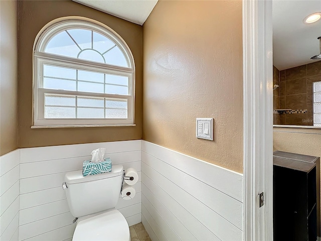 bathroom featuring tiled shower and toilet