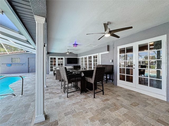 view of patio / terrace featuring glass enclosure, ceiling fan, and french doors