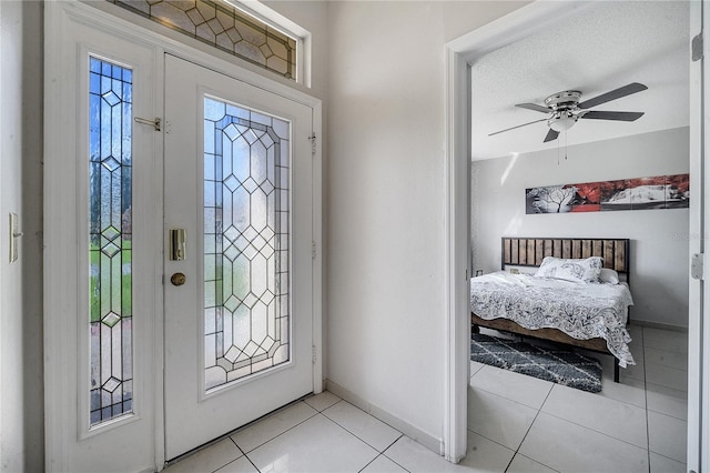 entryway featuring a textured ceiling, a healthy amount of sunlight, light tile patterned flooring, and ceiling fan