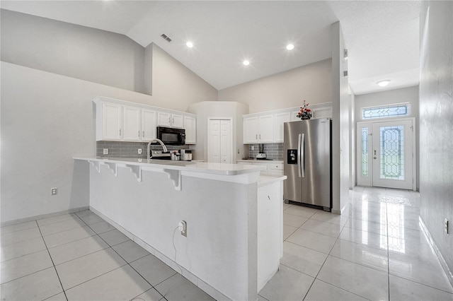 kitchen with light tile patterned floors, backsplash, white cabinetry, and stainless steel refrigerator with ice dispenser