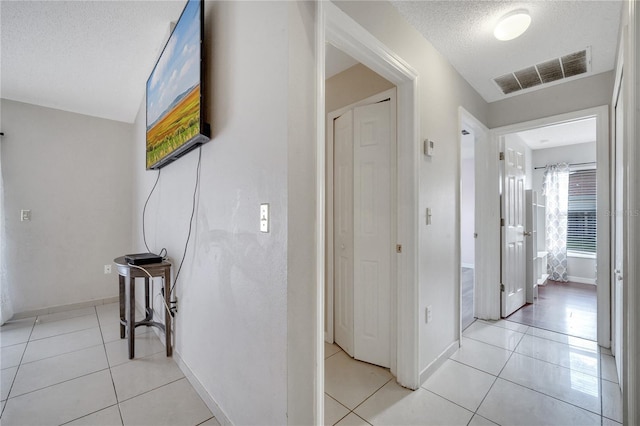 hallway with light tile patterned flooring and a textured ceiling