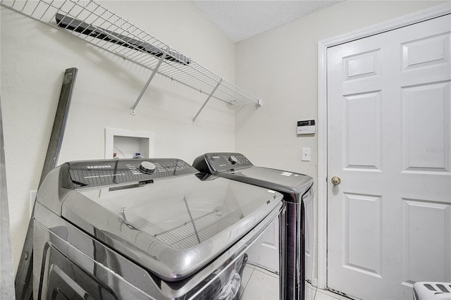 clothes washing area with a textured ceiling and washing machine and clothes dryer