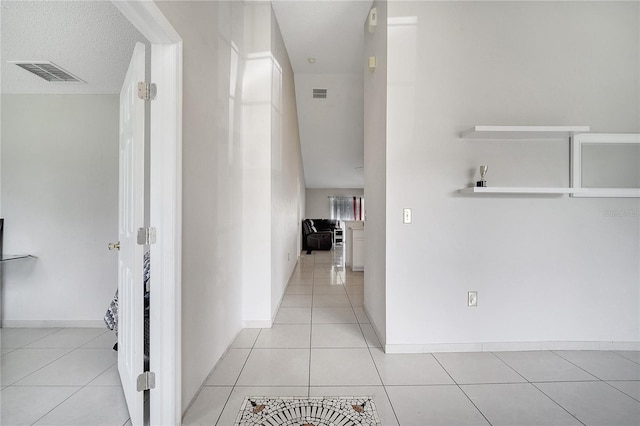 hall with a textured ceiling and light tile patterned floors