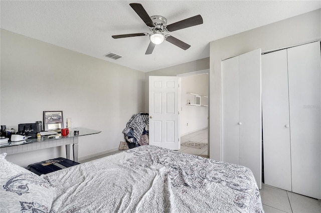 tiled bedroom with multiple closets, a textured ceiling, and ceiling fan