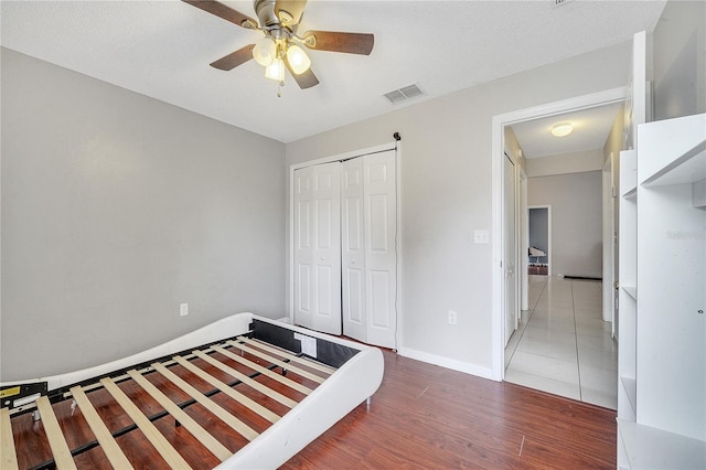 unfurnished bedroom featuring a textured ceiling, hardwood / wood-style floors, ceiling fan, and a closet