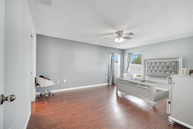 bedroom featuring ceiling fan, dark hardwood / wood-style flooring, and a textured ceiling