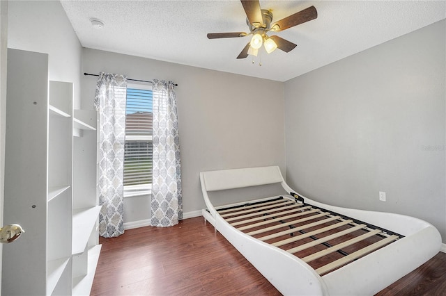 bedroom featuring dark hardwood / wood-style flooring, ceiling fan, and a textured ceiling