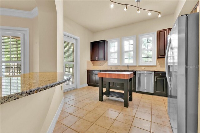 kitchen featuring crown molding, sink, light stone countertops, appliances with stainless steel finishes, and light tile patterned flooring