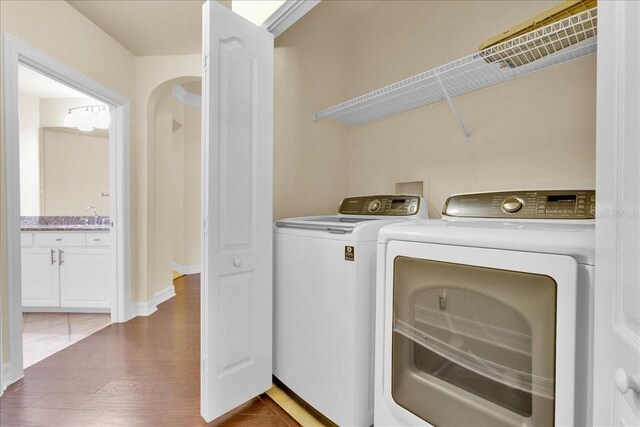 clothes washing area with separate washer and dryer, sink, and dark hardwood / wood-style floors